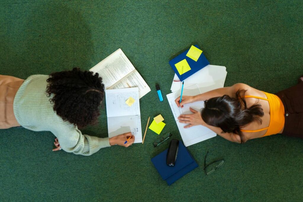 Estudantes revisando matéria para o ENEM com anotações, livros e post-its espalhados enquanto estudam juntas no chão, simbolizando organização e revisão eficiente para Medicina.