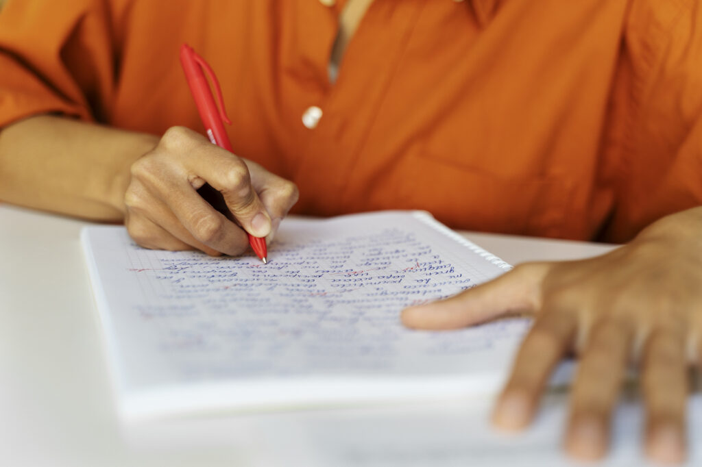 Estudante escrevendo redação do ENEM em caderno durante preparação após a divulgação das notas do ENEM 2025