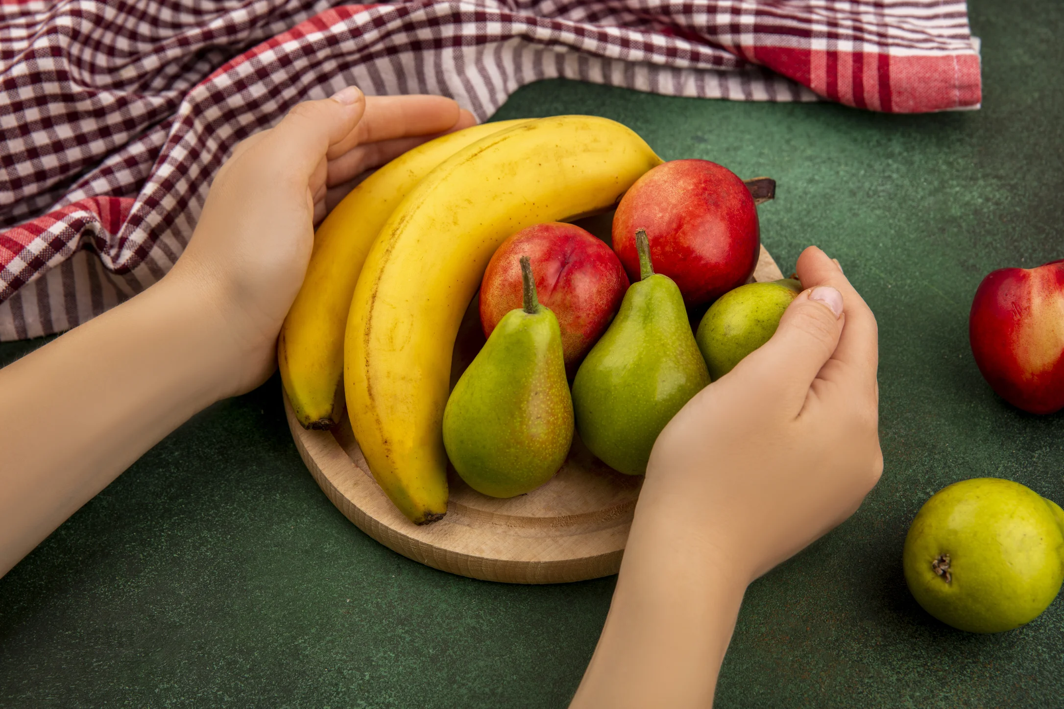 Mãos segurando bandeja com bananas, peras e maçãs, opções do que pode levar no ENEM para manter energia estável