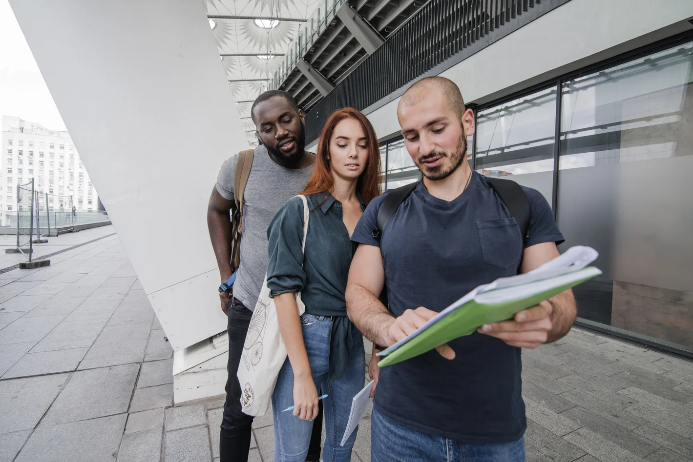 Três estudantes analisando notas e estratégias de inscrição no SISU 2026 do lado de fora de uma universidade.