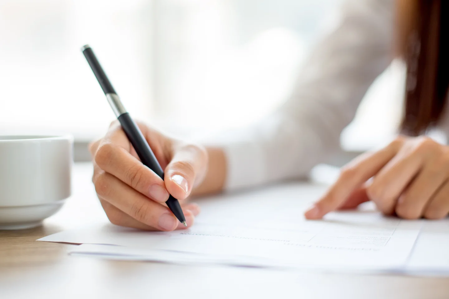 Estudante escrevendo redação do ENEM com atenção após interpretar os textos motivadores da coletânea